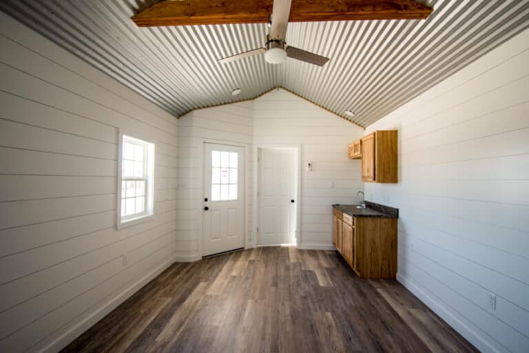 Outpost cabin interior with wood-style flooring, white walls, and a small kitchenette.